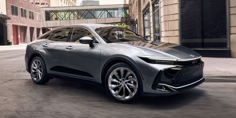 A silver 2025 Toyota Crown with a black hood driving on a city street