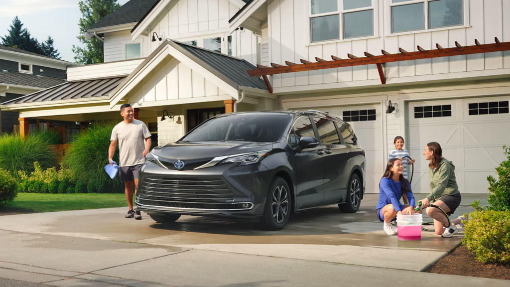 Family washing a new 2025 Toyota Sienna parked outside their house