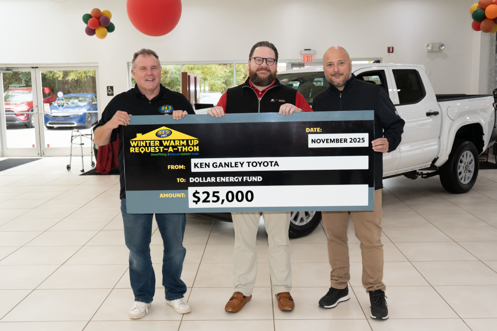 Three dealership salesmen holding a twenty five thousand donation check for Dollar Energy Fund in Pennsylvania, USA.